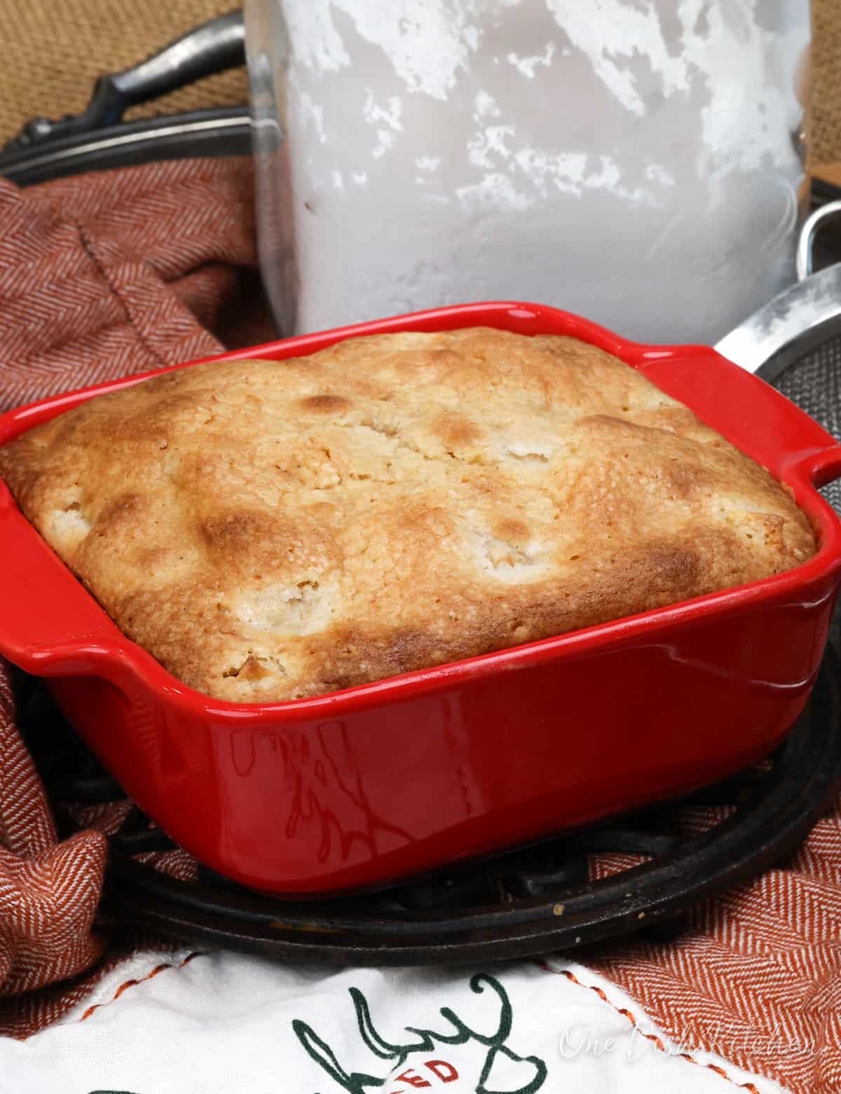 a small apple cake in a red baking dish on a silver tray.