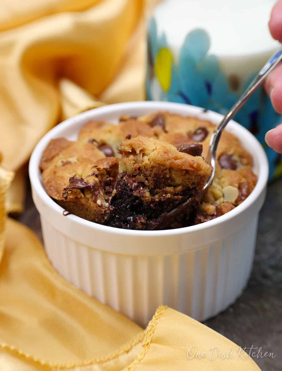 a spoonful of brownie and cookie above a brookie in a ramekin.