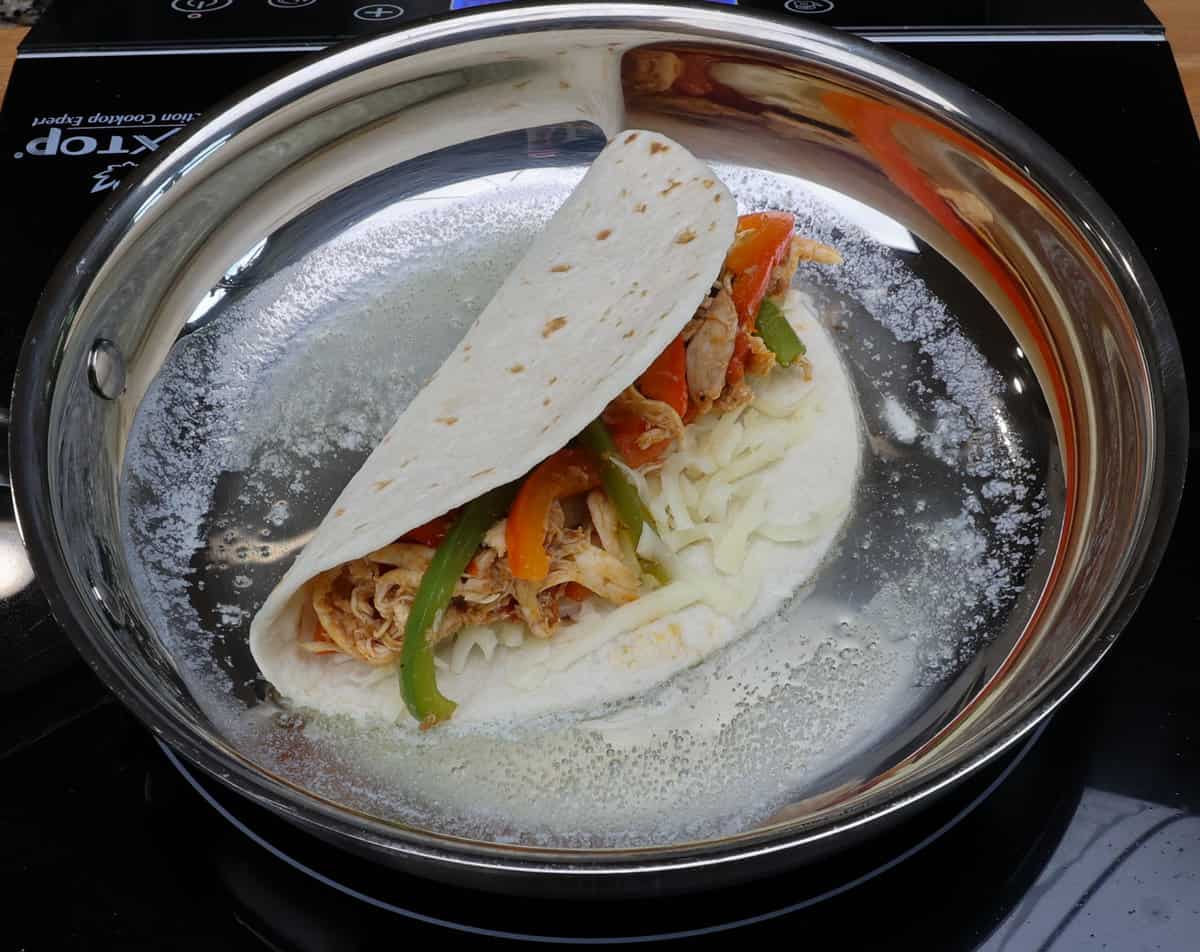 one chicken taco in a buttered skillet.