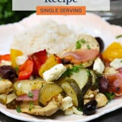 greek chicken with vegetables and rice on a white plate.