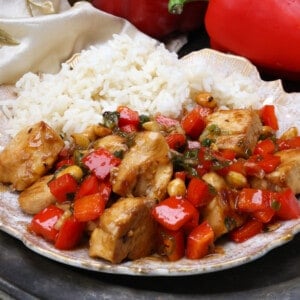 kung pao chicken on a white plate next to a side of white rice.