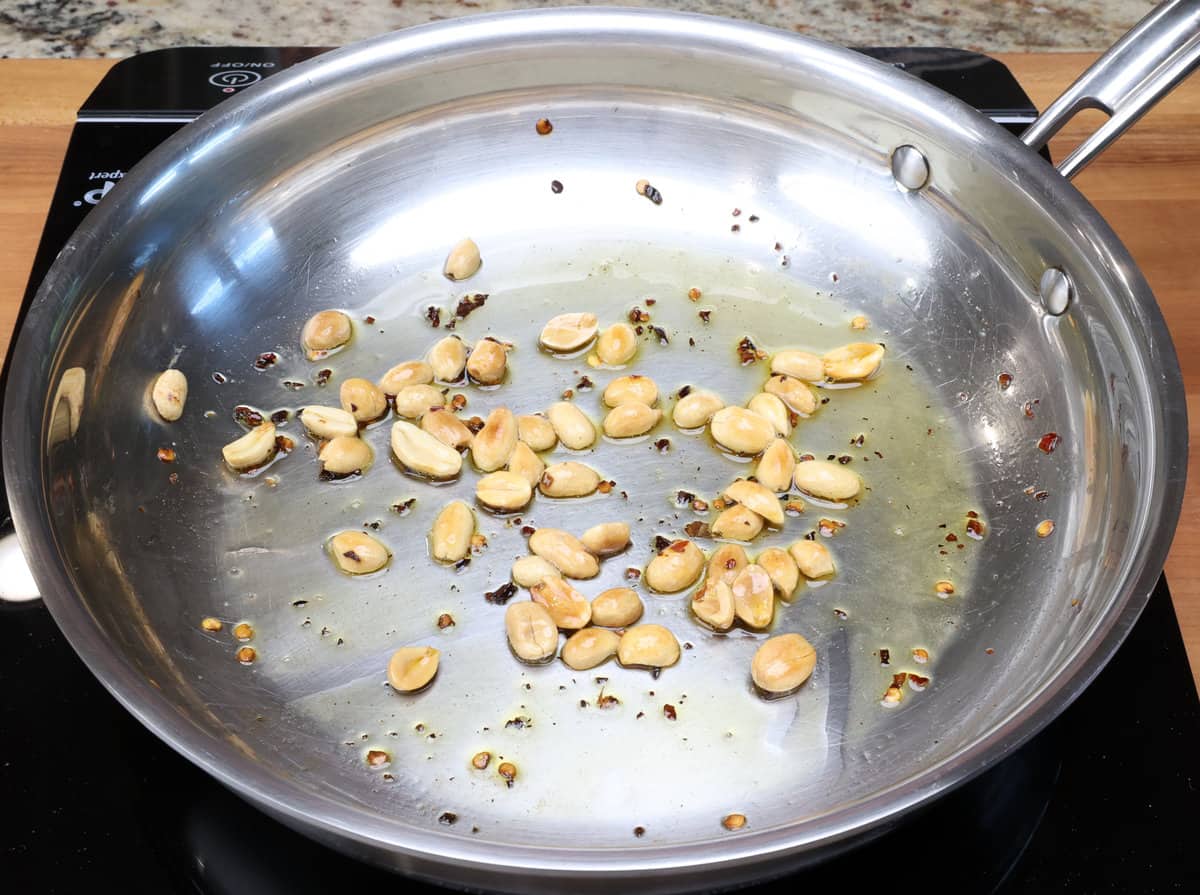 peanuts and red pepper flakes browning in a skillet.