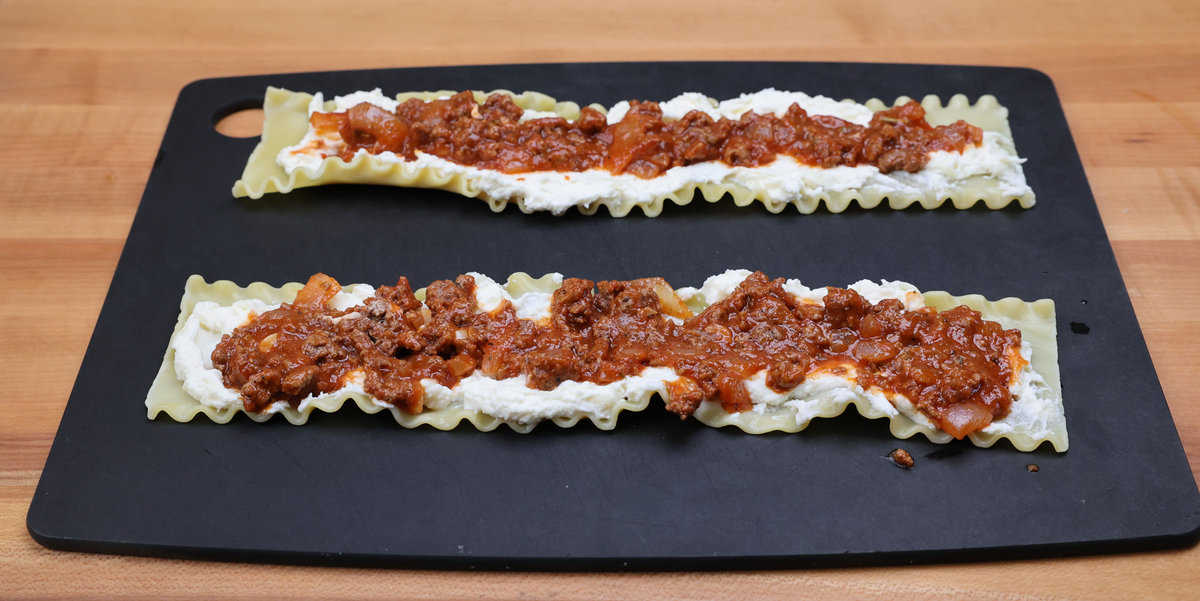 meat sauce and cheeses spread over two lasagna noodles.