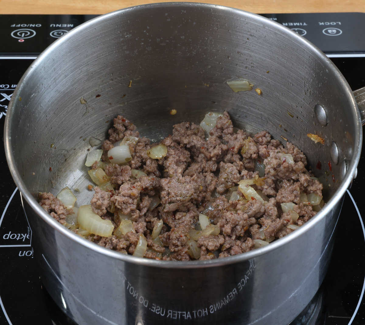 ground beef, onions, garlic, and seasonings cooking in a small pot.