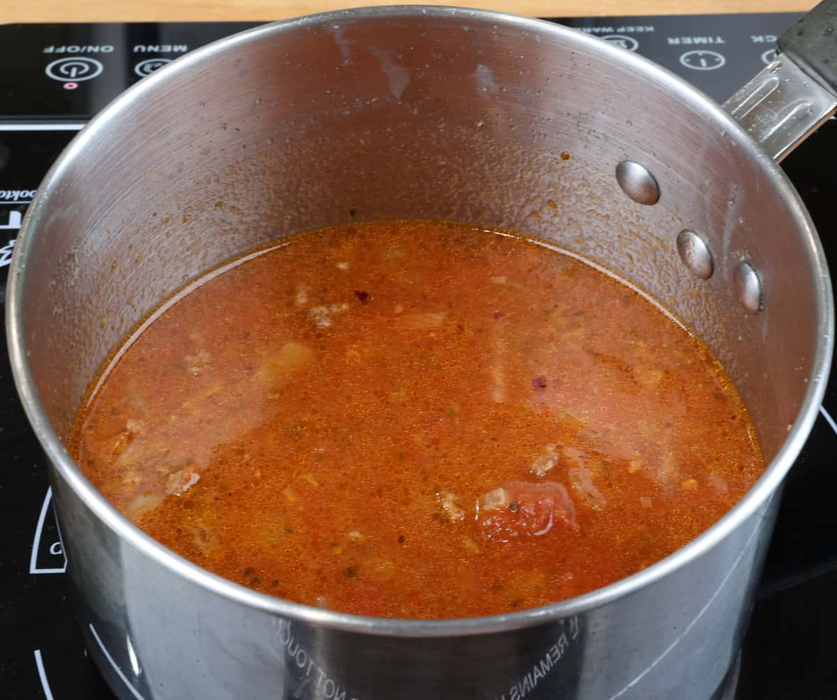 tomato sauce and ground beef simmering in a small pot.