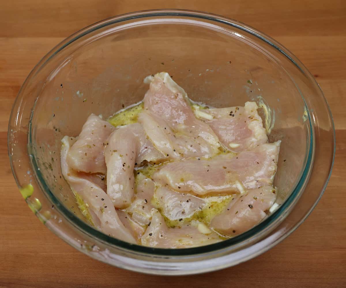 chicken strips marinating in a bowl.