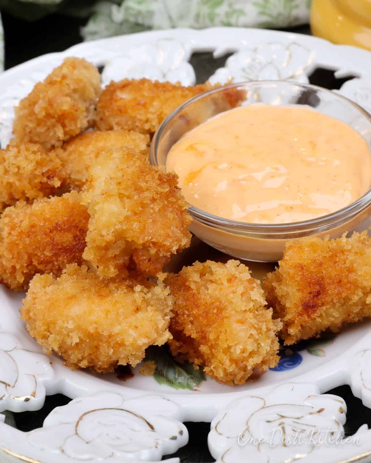 a plate of crispy chicken nuggets next to a dipping sauce.