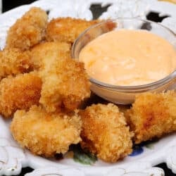 a plate of crispy chicken nuggets next to a dipping sauce.