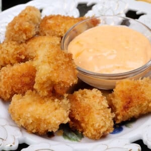a plate of crispy chicken nuggets next to a dipping sauce.