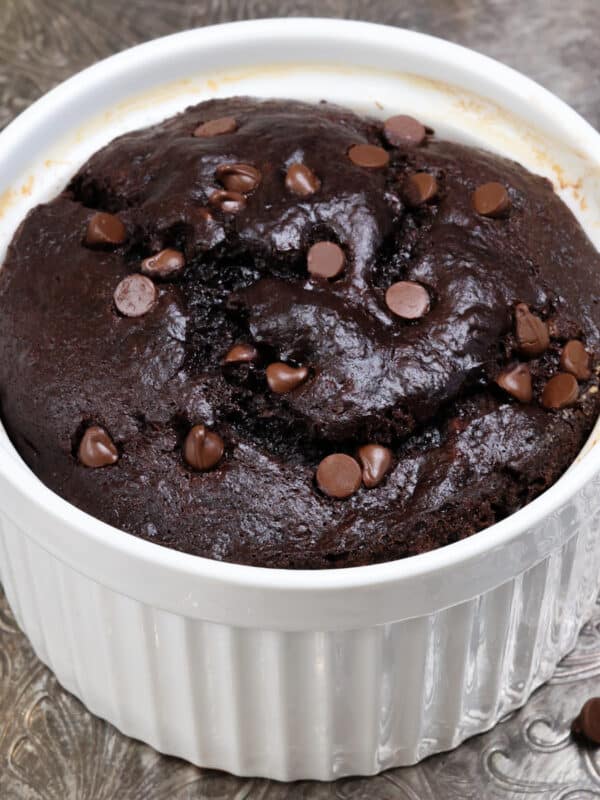 a small chocolate banana bread topped with chocolate chips in a white ramekin.