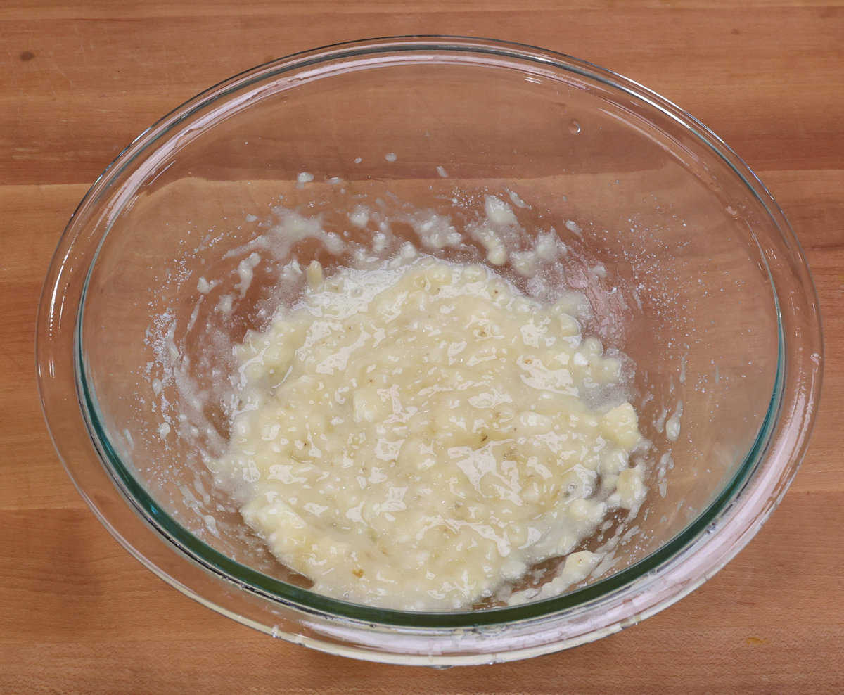 mashed banana and sugar mixed together in a mixing bowl.