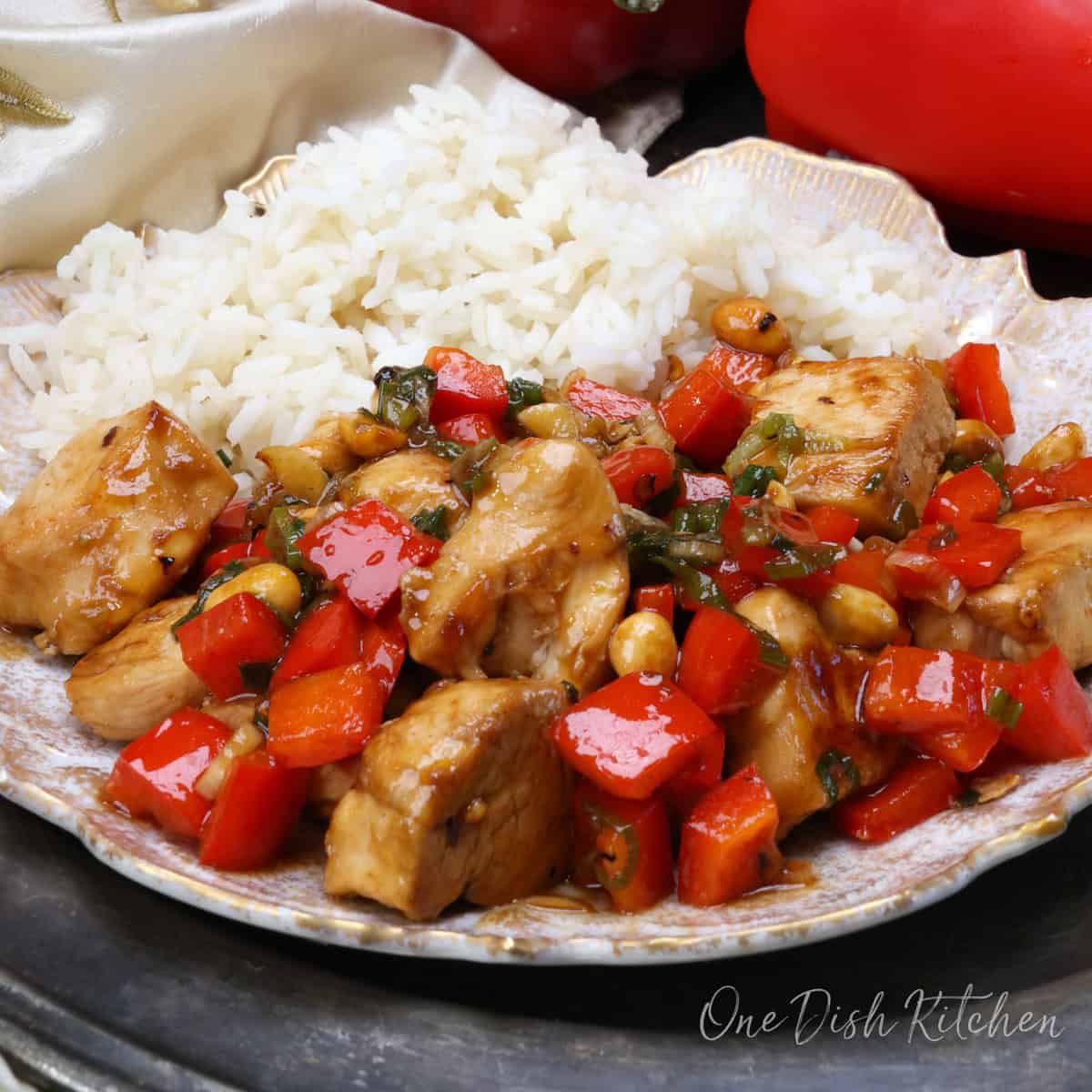 kung pao chicken on a white plate next to a side of white rice.
