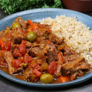 a plate of ropa vieja and rice on a silver tray.