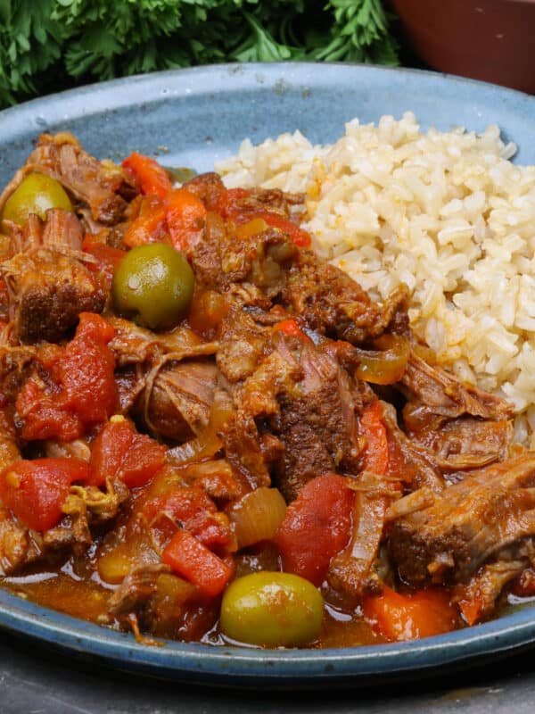 a plate of ropa vieja and rice on a silver tray.