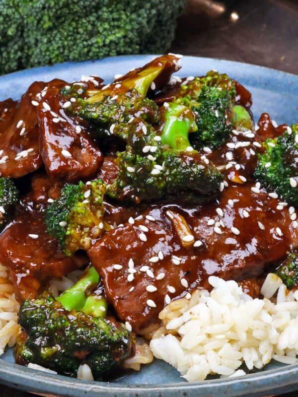 beef and broccoli over white rice on a blue plate.
