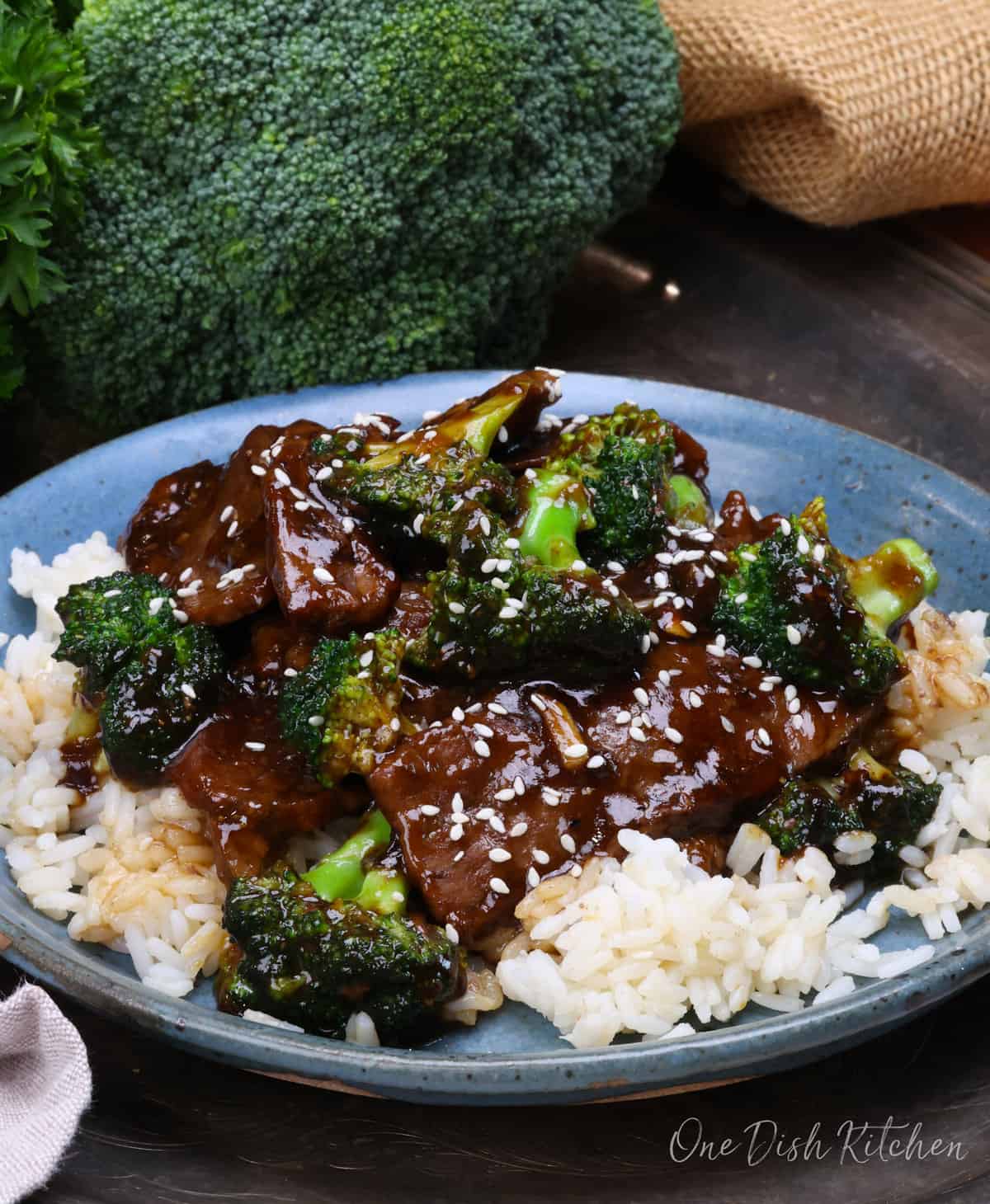 beef and broccoli over white rice on a blue plate.