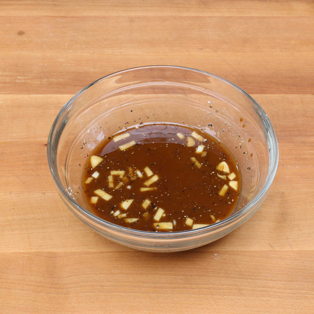 a bowl of stir fry sauce on a wooden counter.
