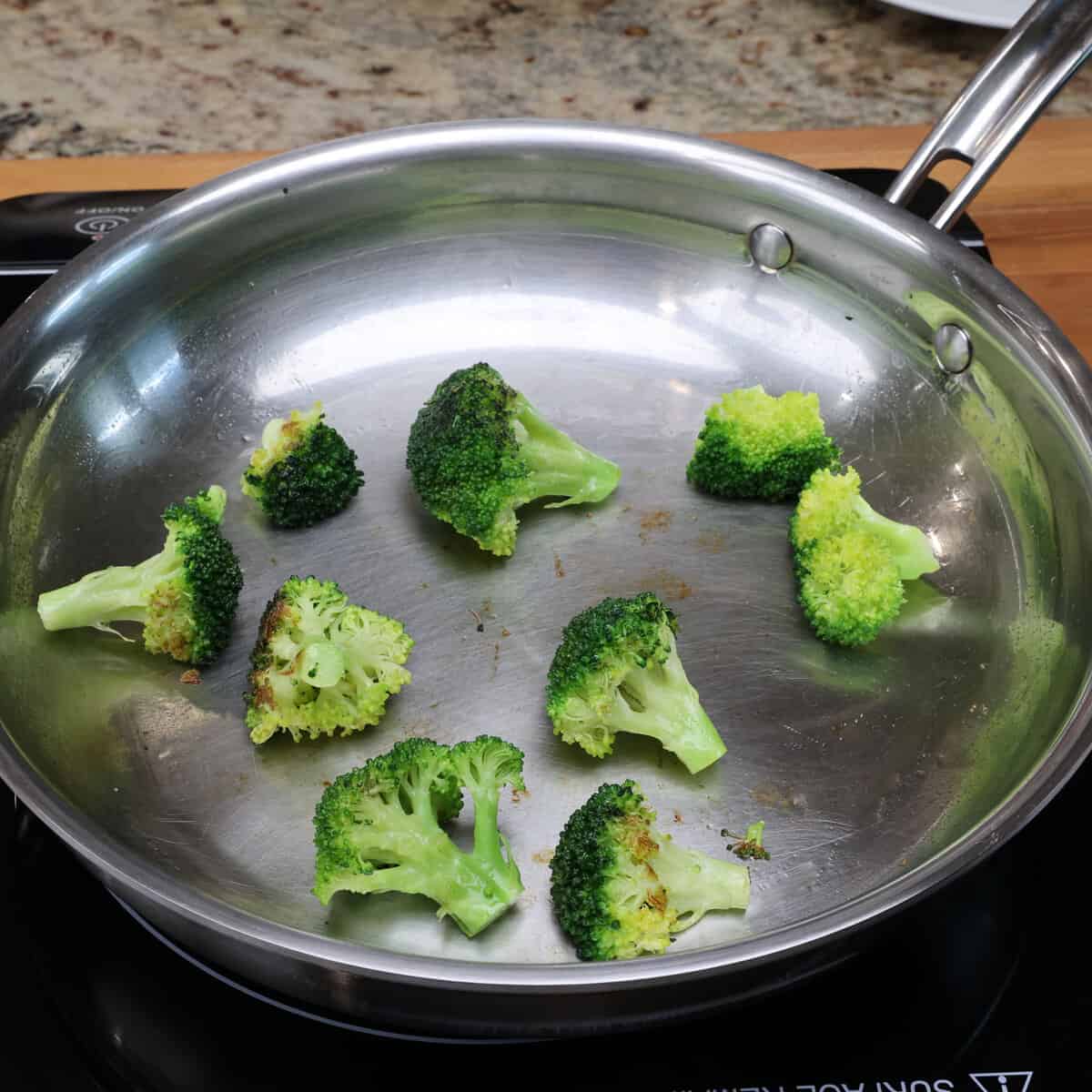 broccoli florets cooking in a skillet.