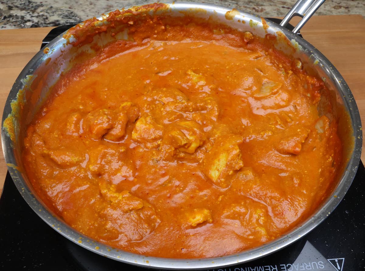 Chicken tikka masala simmering in a skillet on the stove.
