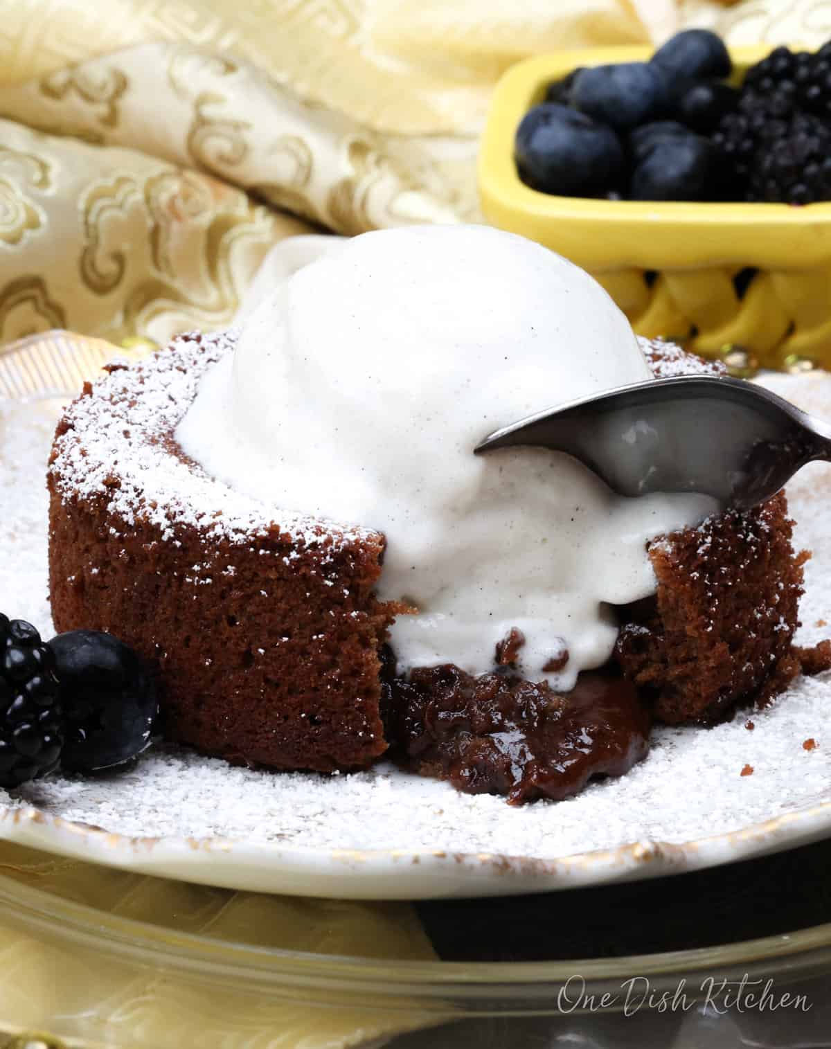 lava cake topped with ice cream and melted chocolate pouring out of the cake on a white plate.