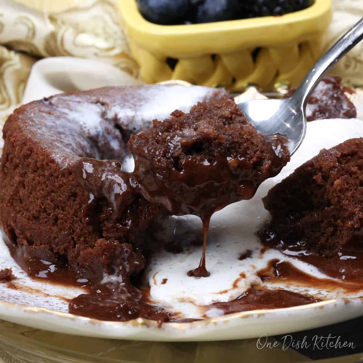 cutting into a chocolate lava cake with the melted chocolate dripping off the spoon.