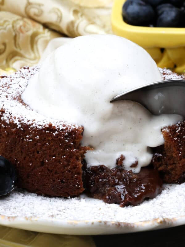 lava cake topped with ice cream and melted chocolate pouring out of the cake on a white plate.