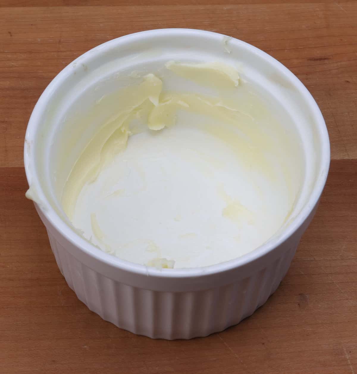 a generously buttered ramekin on a kitchen counter.