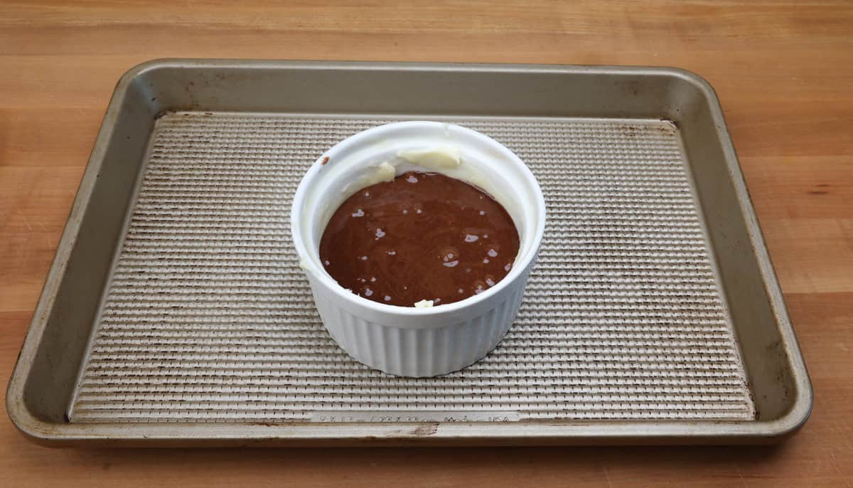 unbaked chocolate lava cake in a ramekin on a baking sheet.