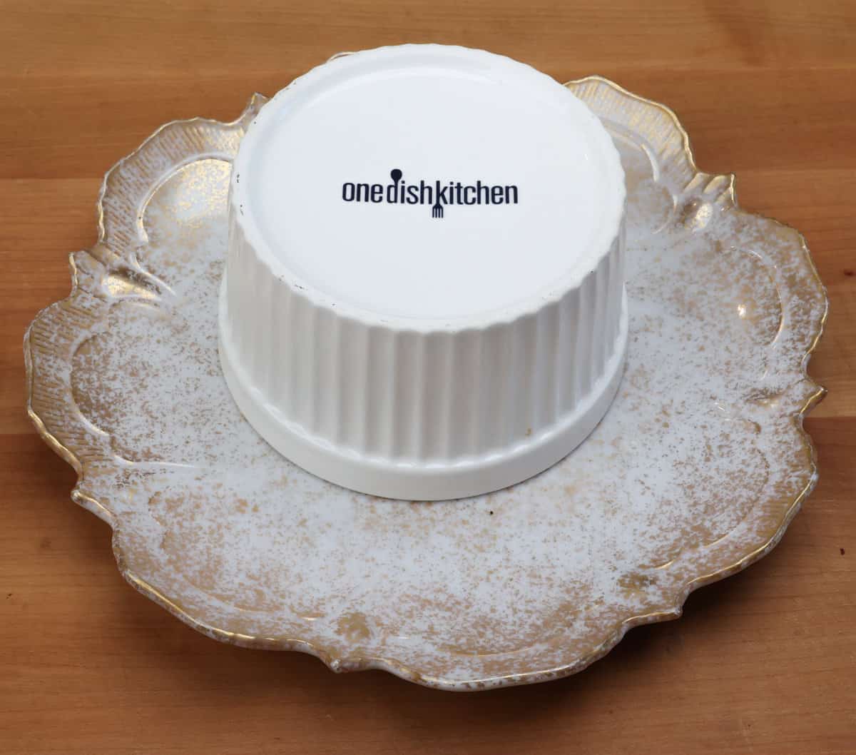 a ramekin inverted on a plate waiting for its release from the ramekin.
