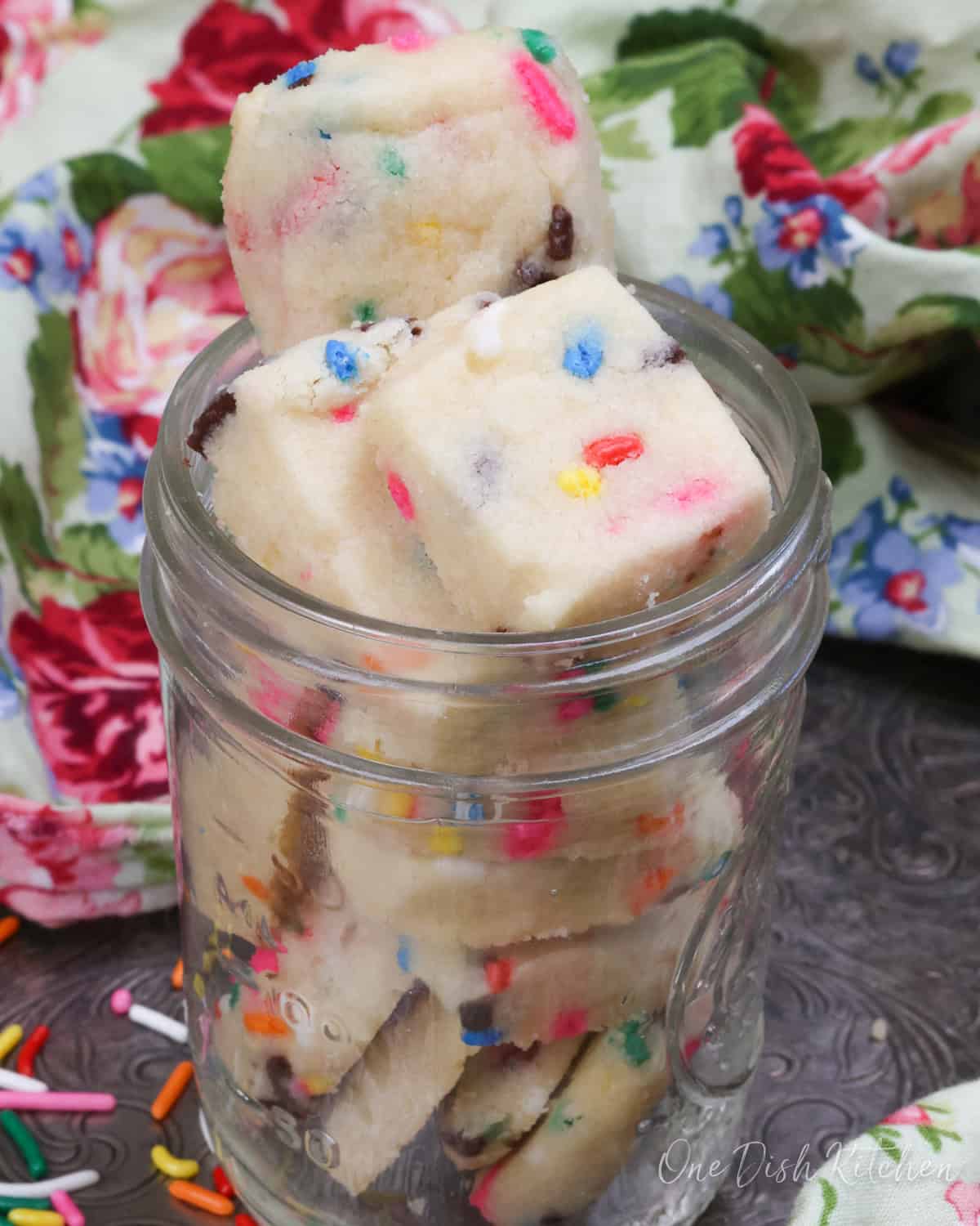 shortbread cookie bites in a mason jar next to a flowered napkin.