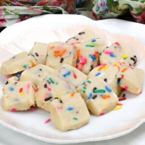 a plate of funfetti shortbread bites next to a container of colorful sprinkles.