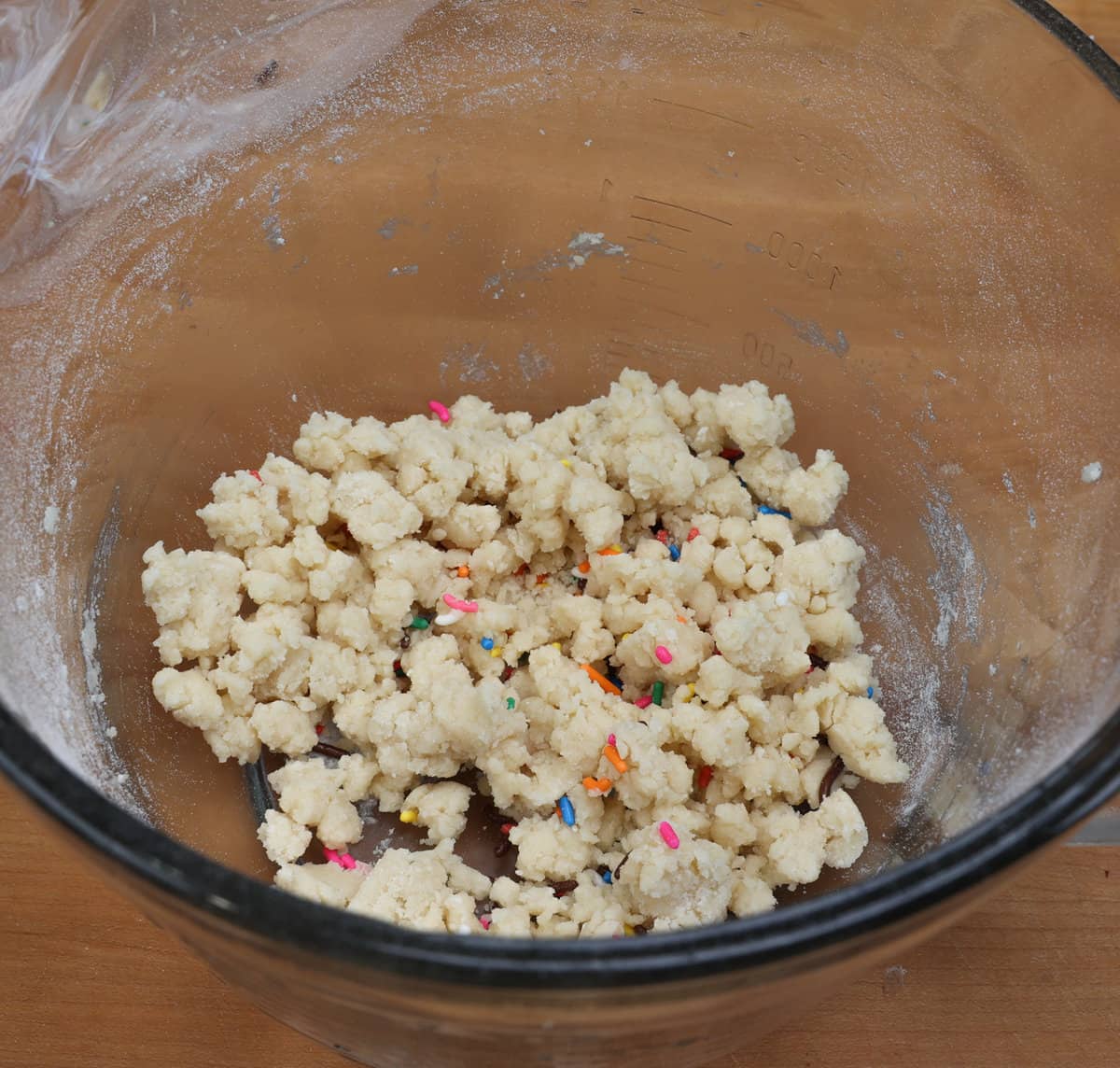 funfetti sprinkles mixed with shortbread cookie dough in a mixing bowl.