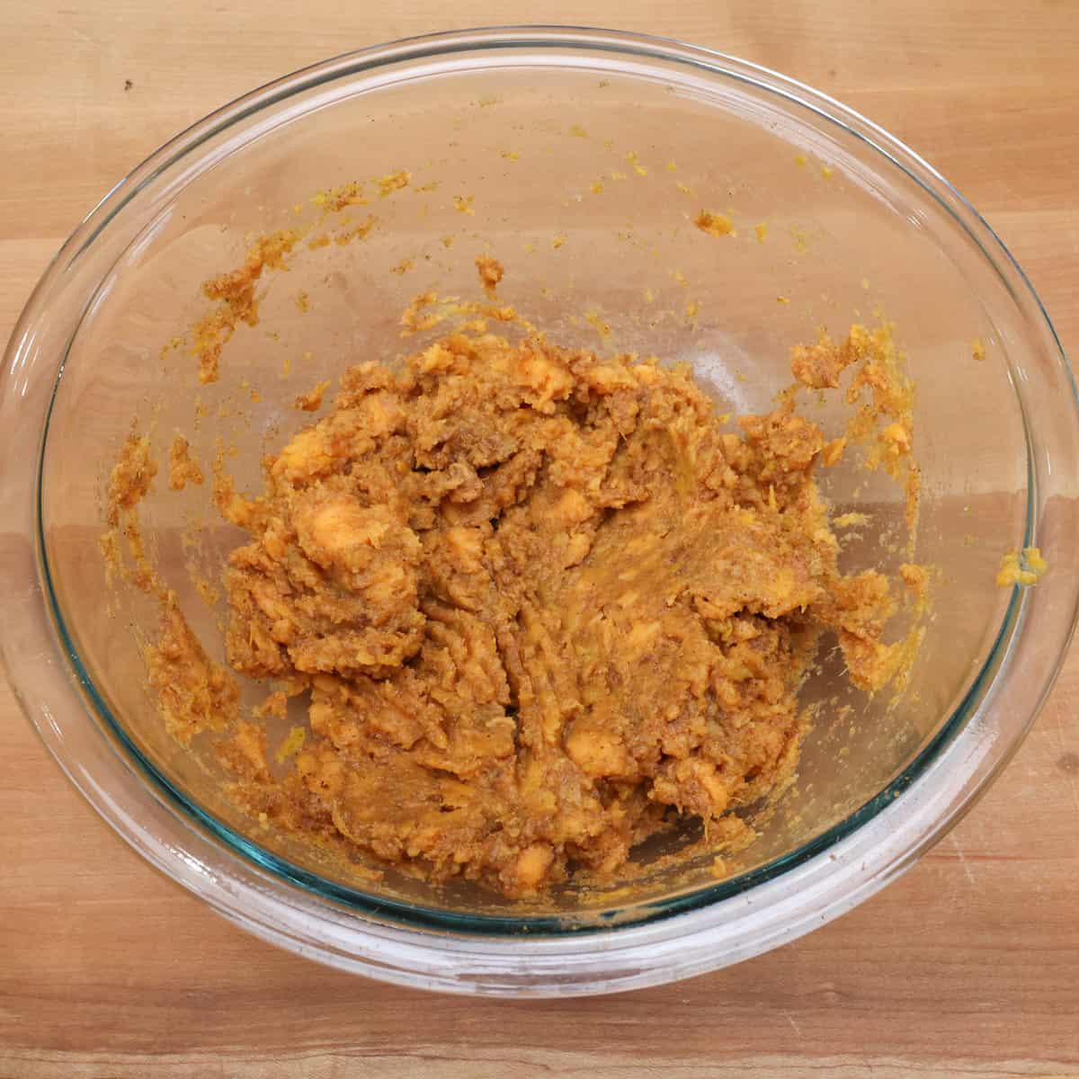 glass bowl with mashed sweet potatoes mixed with the dry ingredients.