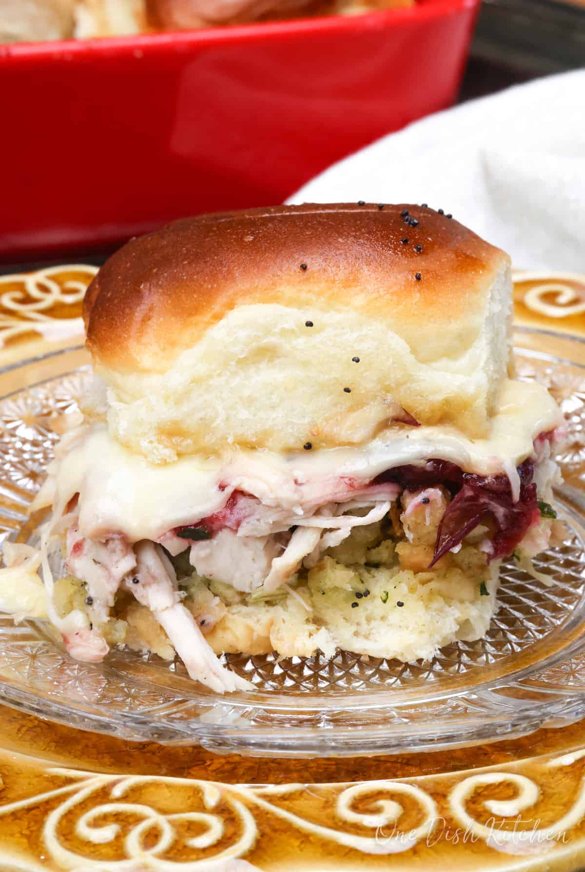 a turkey slider on a plate filled with leftover turkey, cranberry sauce, cheese, and stuffing.