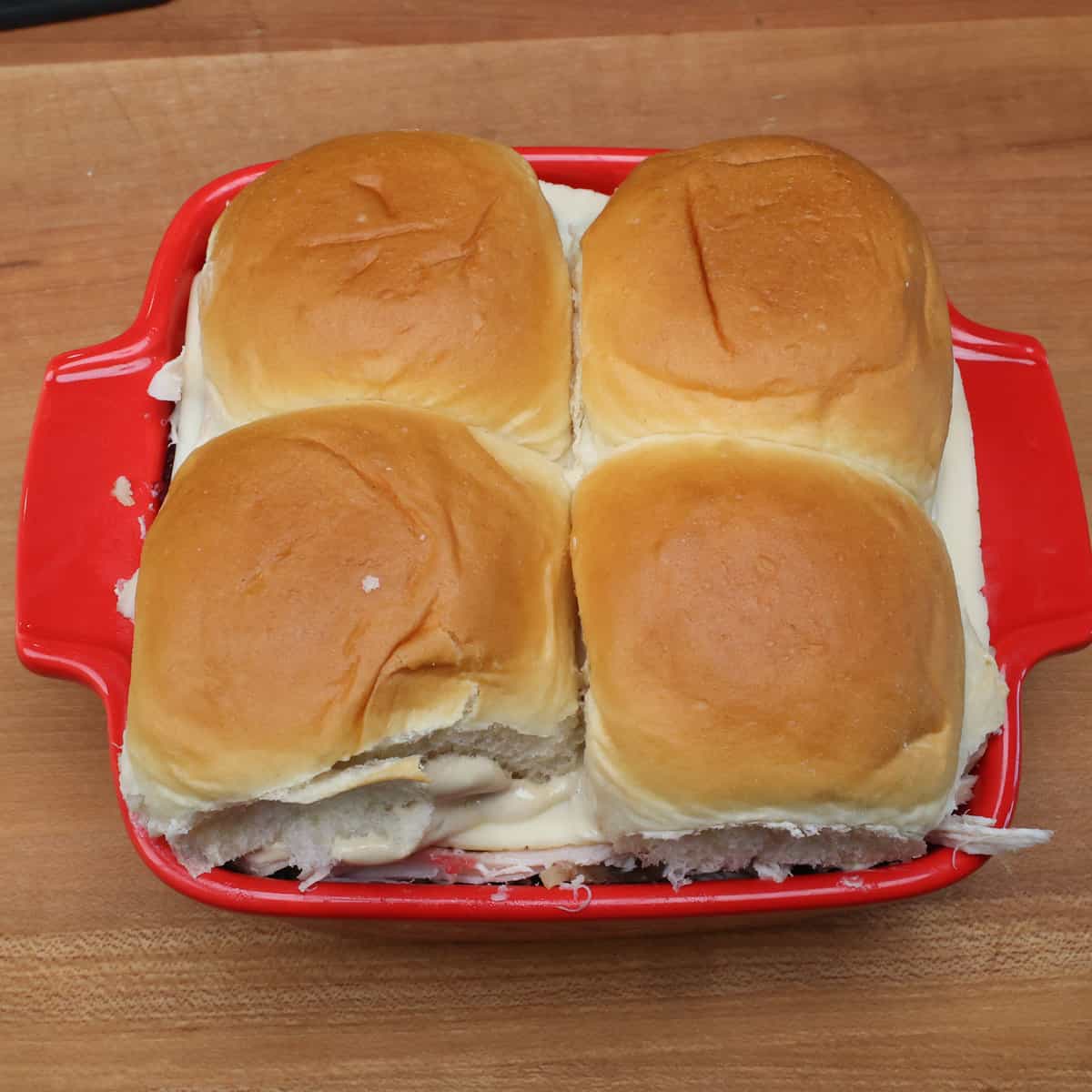 four thanksgiving turkey sliders in a small red baking dish.