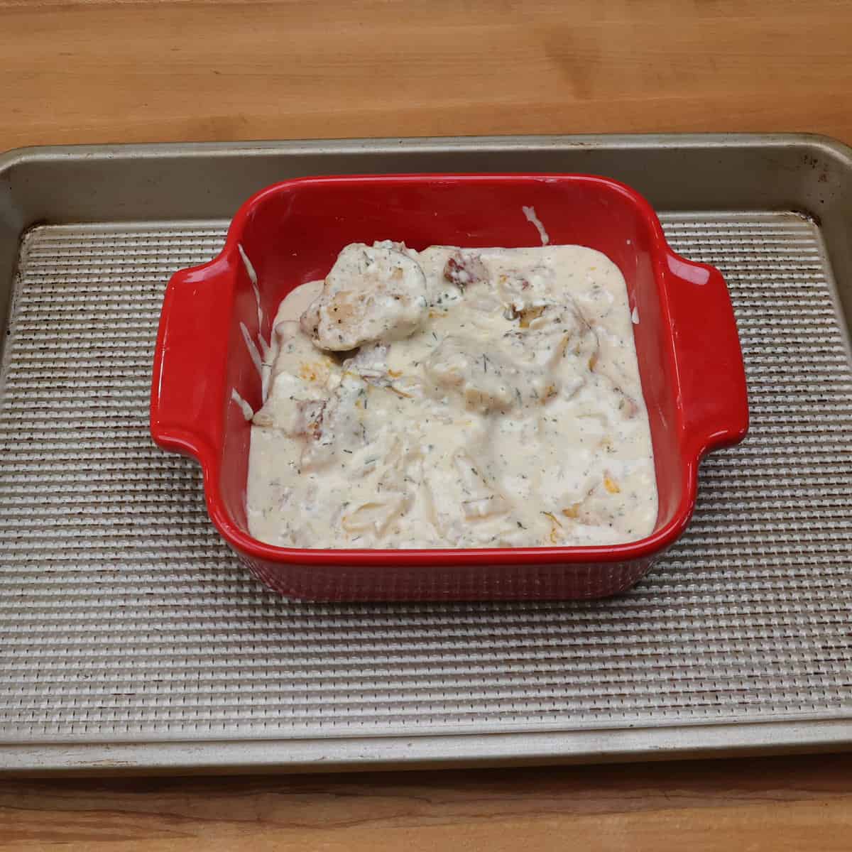 crack chicken in a small red baking dish.