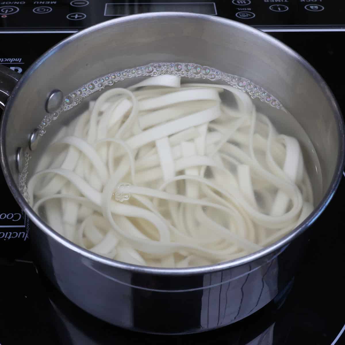 lo mein noodles cooking in a pot.