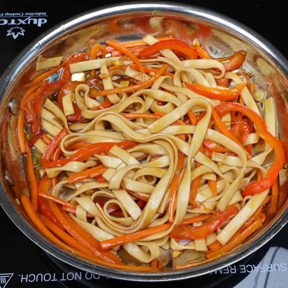 lo mein noodles combined with the sauce in a skillet.
