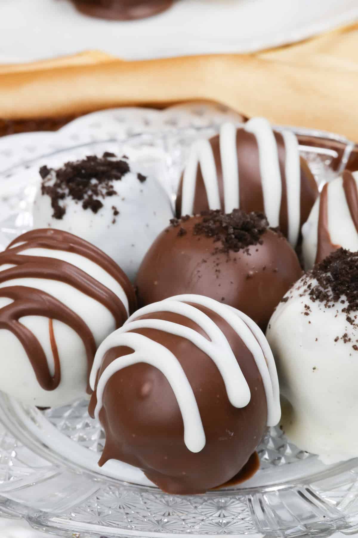 chocolate oreo truffles on a plate drizzled with white chocolate.