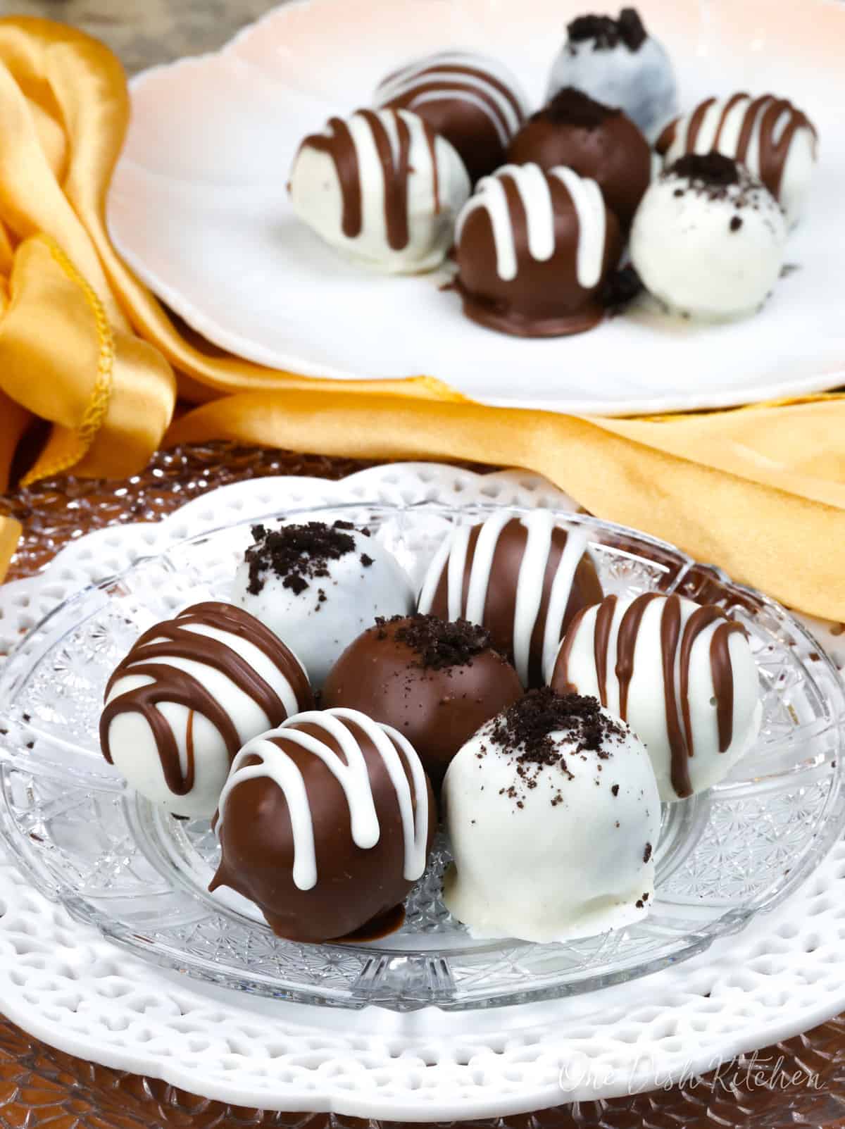 a glass dish with two dark chocolate oreo truffles and 4 white chocolate covered truffles.