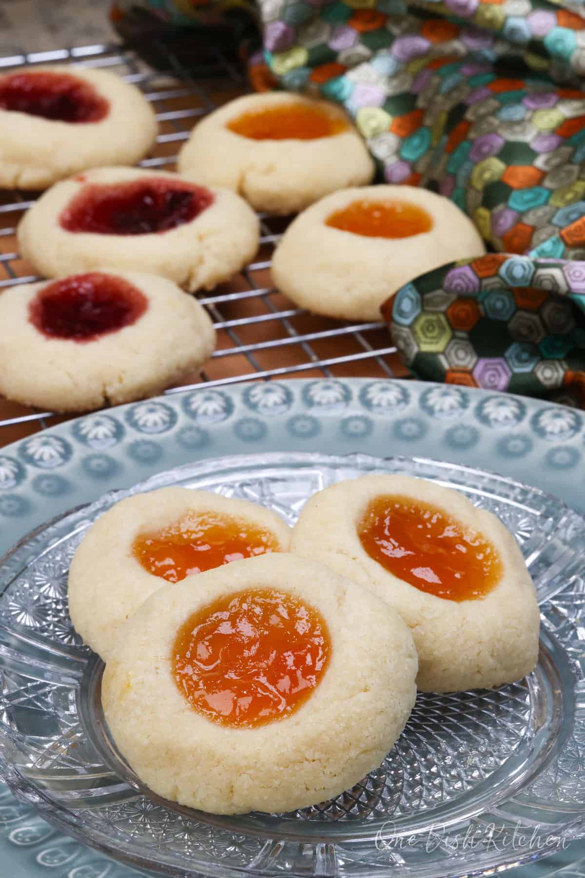 an assortment or raspberry filled thumbprint cookies next to cookies filled with orange marmalade.