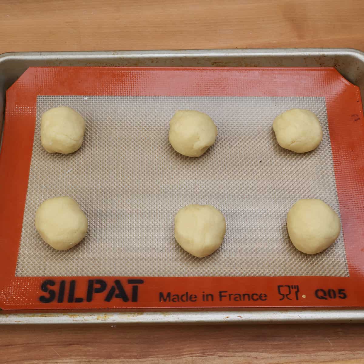 rolled balls of cookie dough on a baking sheet.
