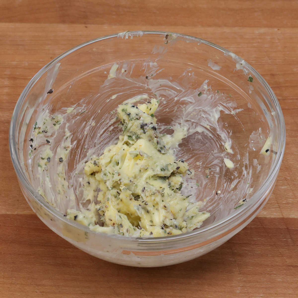 a small bowl with softened butter, tarragon, garlic powder, salt and pepper mixed together.