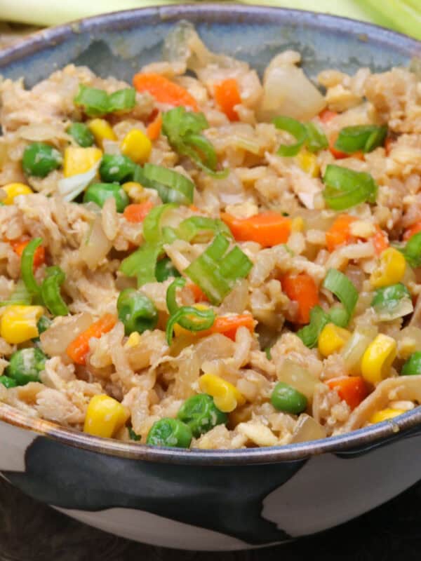 a bowl of chicken fried rice next to carrots and celery and a brown napkin.