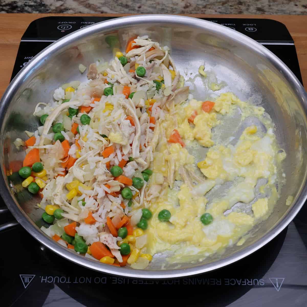 chicken fried rice cooking in a skillet with eggs just added.