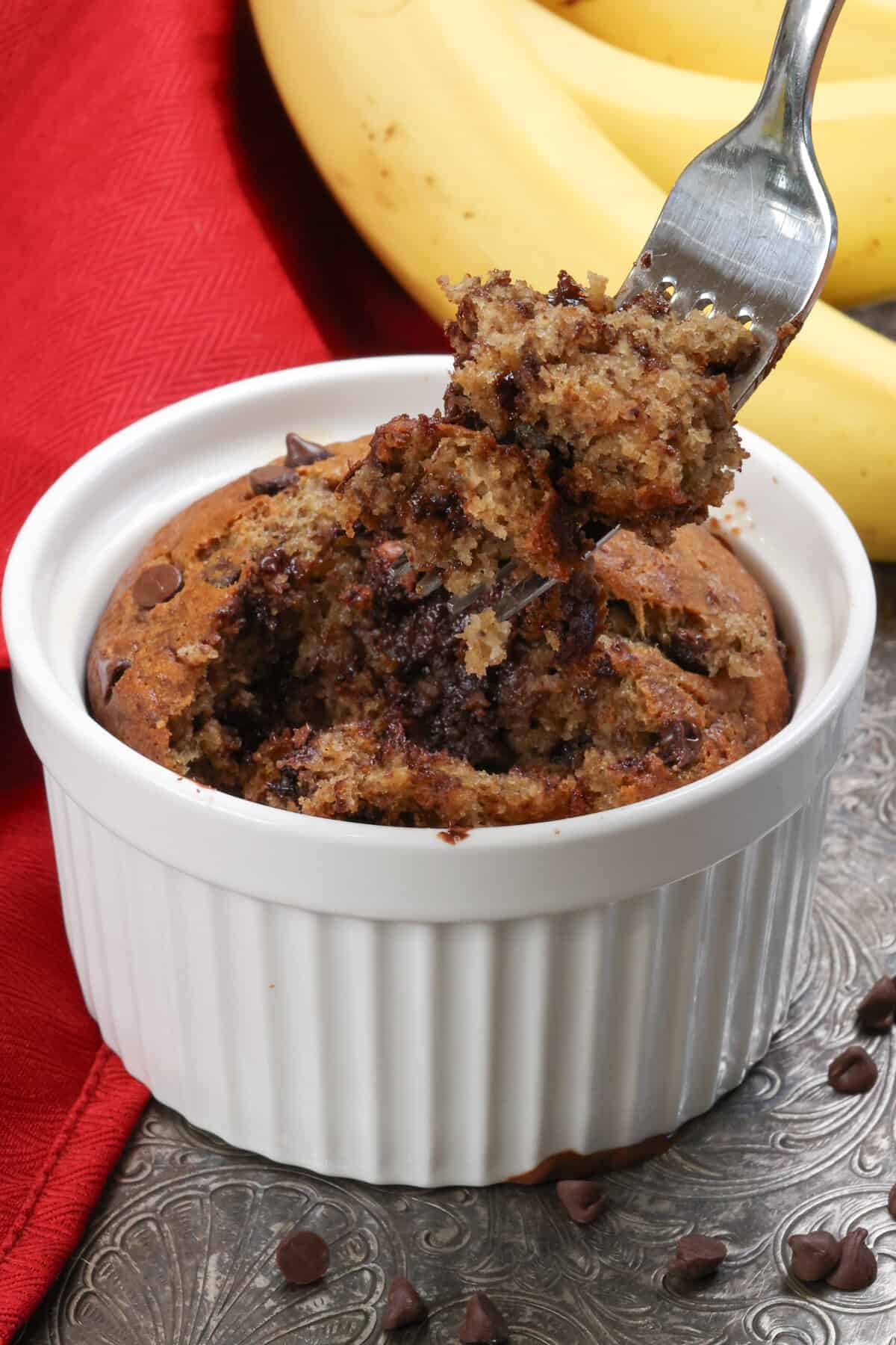 a fork filled with chocolate chip banana bread over the ramekin with the remaining banana bread.