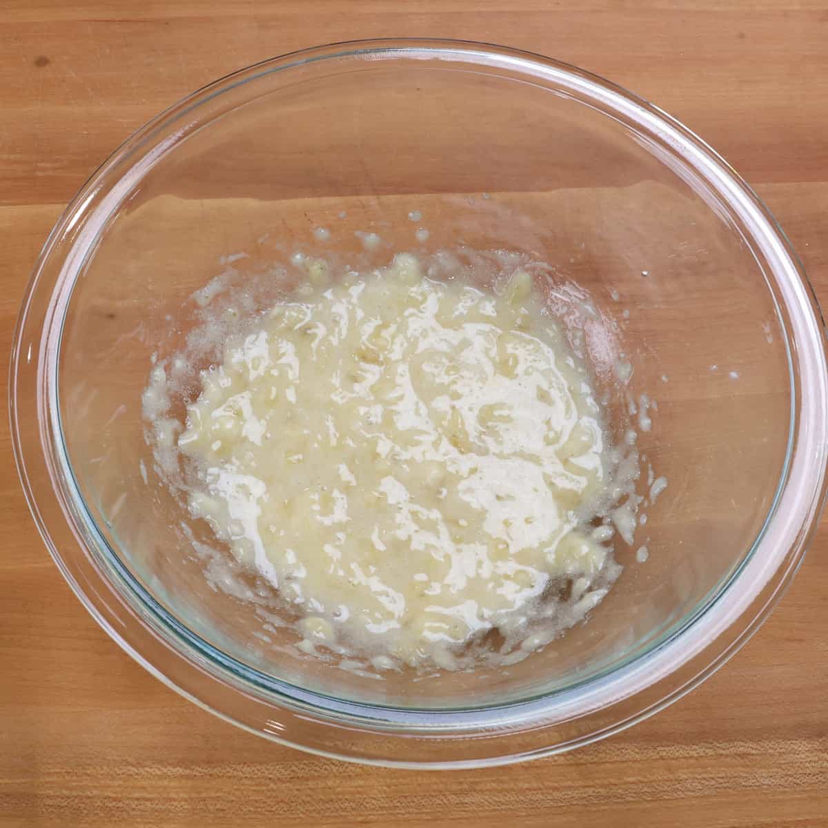 sugar and a mashed banana mixed together in a clear bowl.