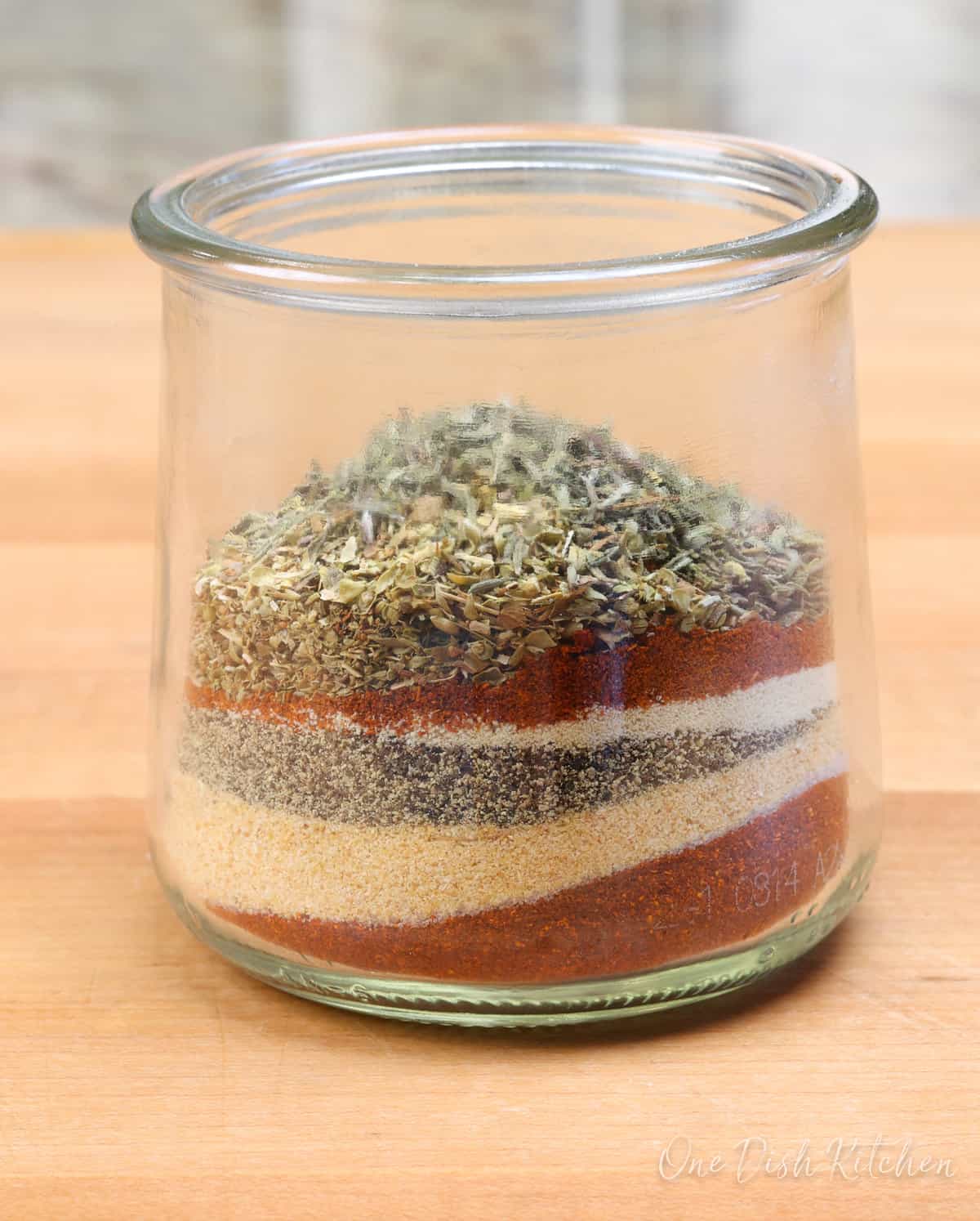 a small jar filled with layers of the spices found in creole seasoning.