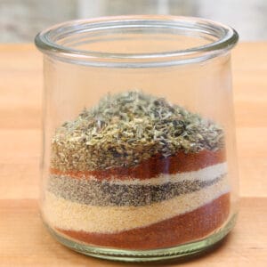 a small jar filled with layers of the spices found in creole seasoning.