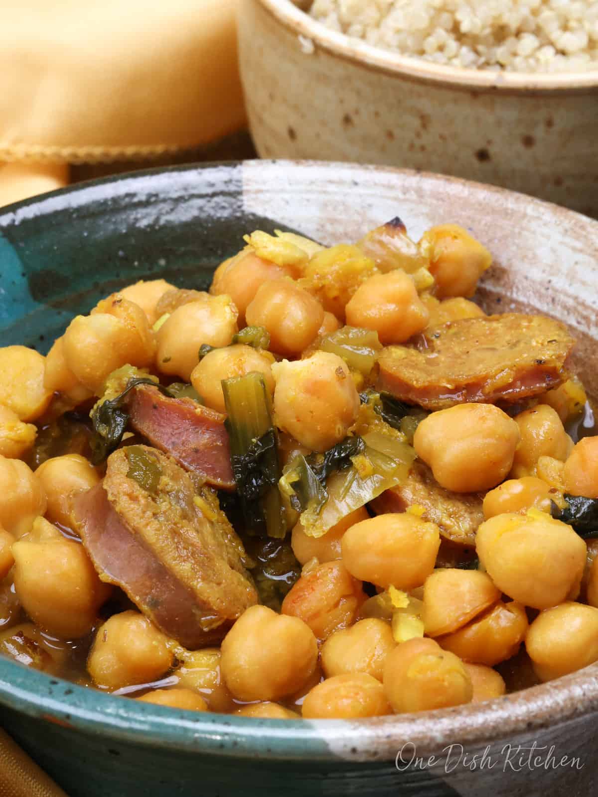 a close up picture of a bowl of chickpeas and sausage with dandelion greens.